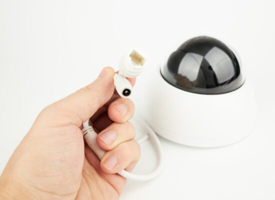 person holds plugs for communicate security ip camera. lan and power plugs close up.